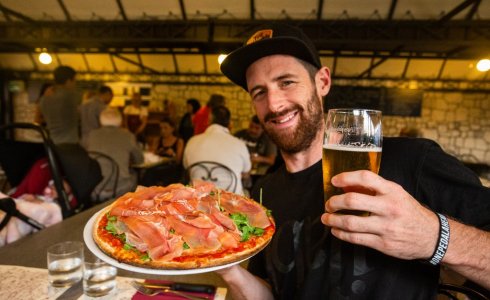 Happy chap with a pizza and and a beer in molini | MTB Beds